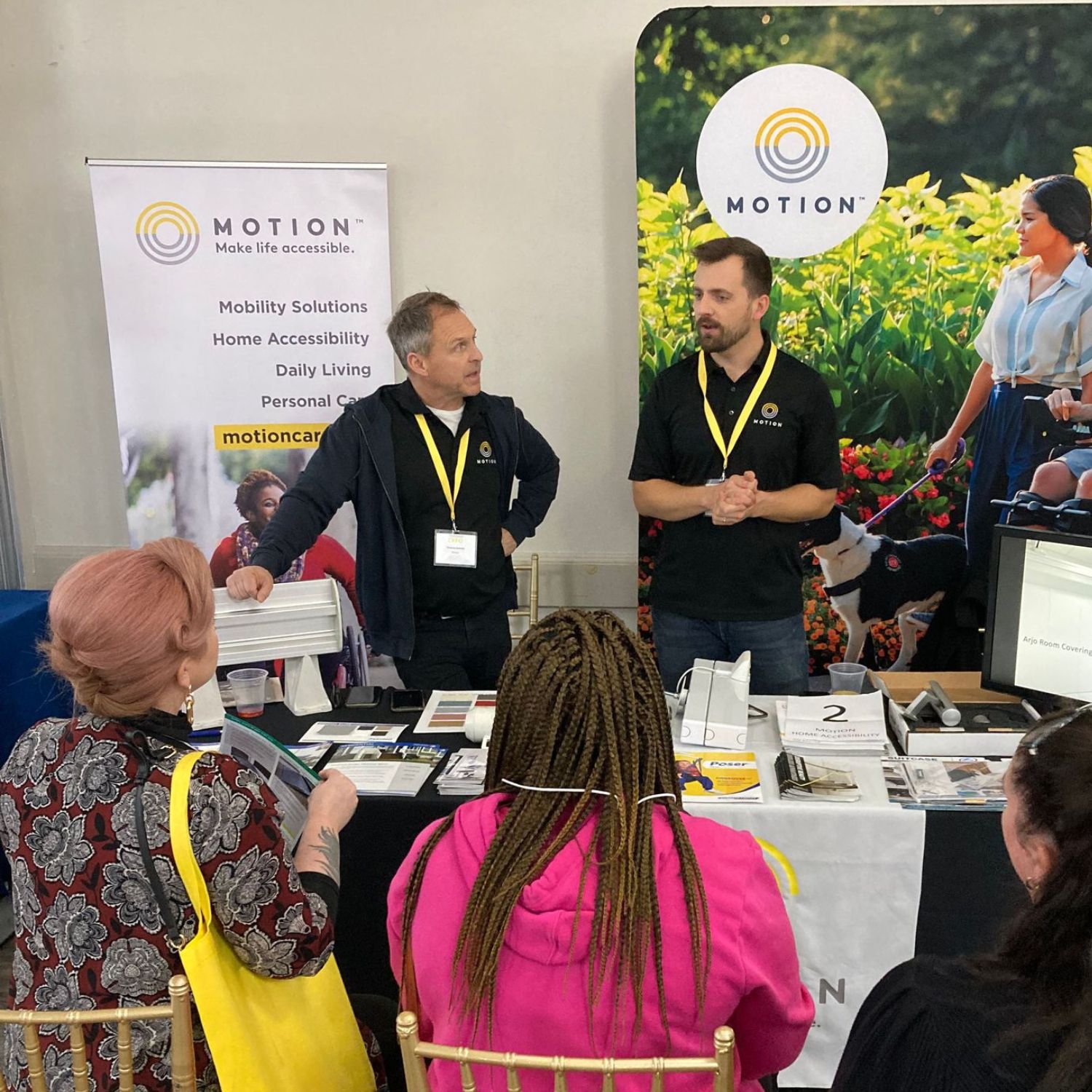 Two Motion employees presenting to three attendees at a Motion Rehab Expo.