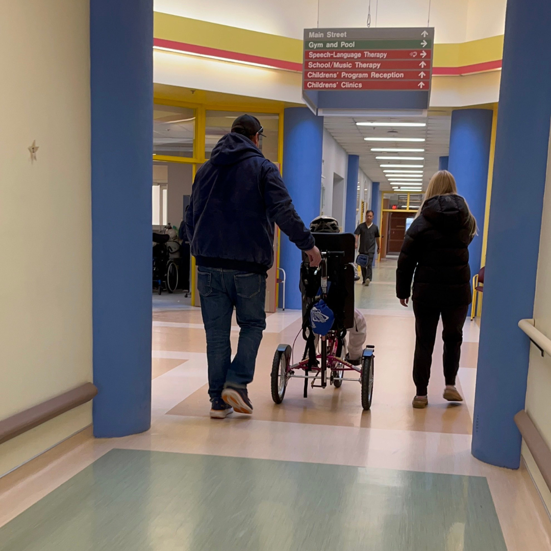 Anika leaving with her parents in her tricycle.