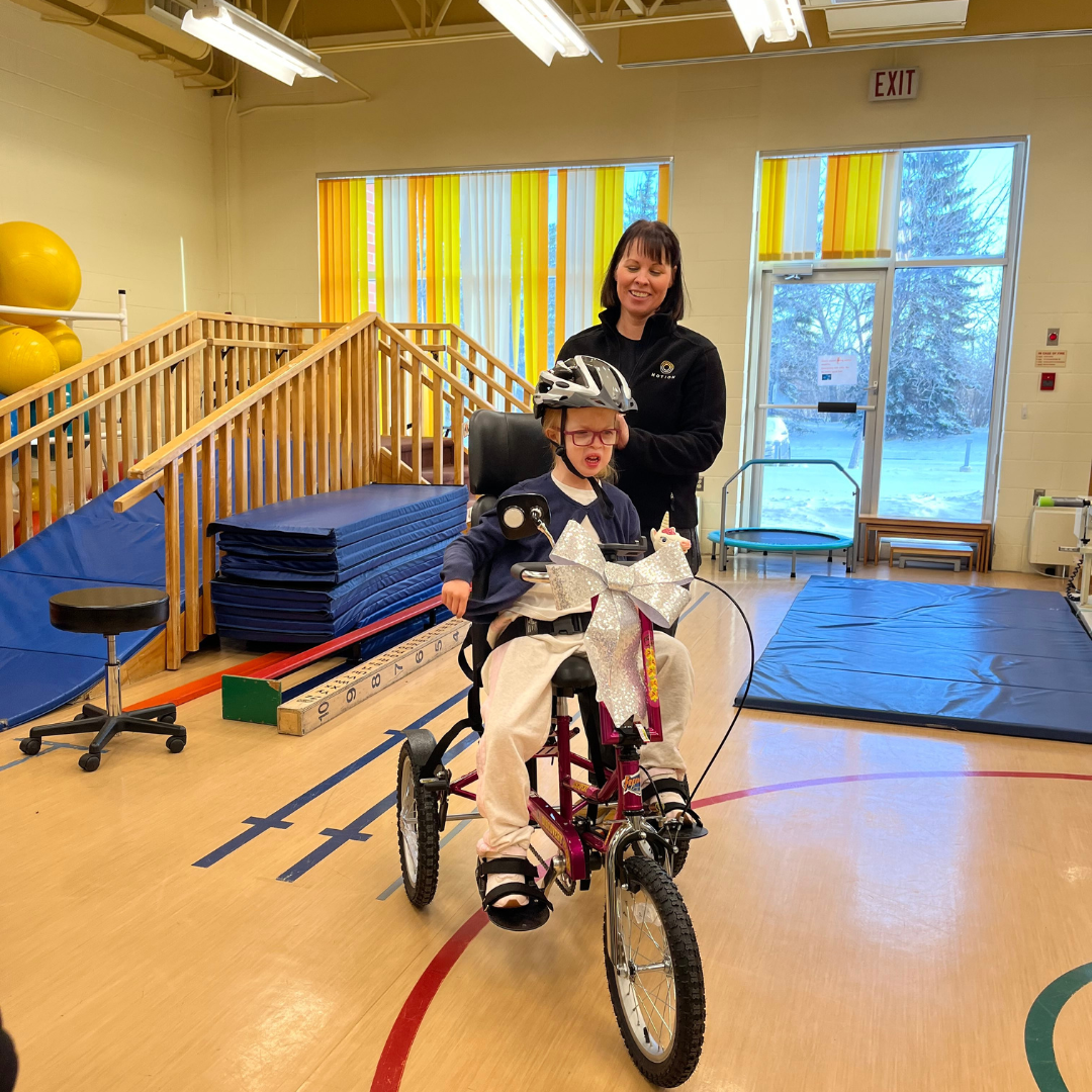 Anika in her new tricycle with a team member from Motion.